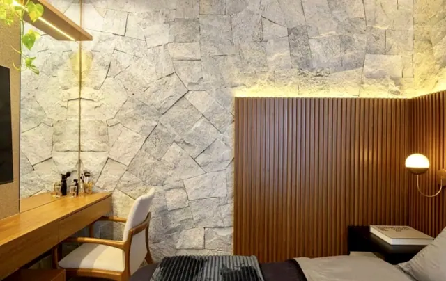 Parede interna com pedra Miracema branca gnaisse em formato irregular com iluminação indireta e painel ripado